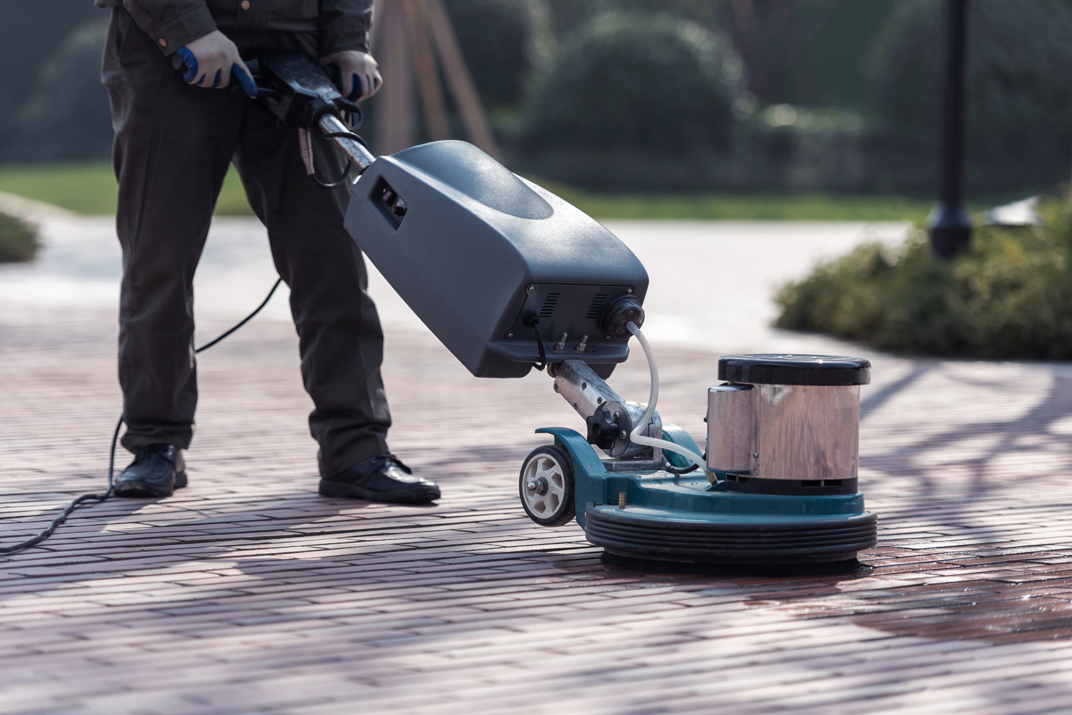 Cleaning staff uses push floor scrubber to clean red floor tiles
