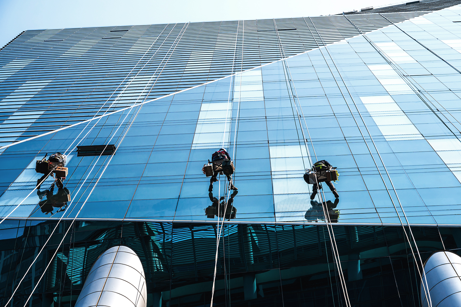 Group of high rise workers hanging on access rope cleaning highr